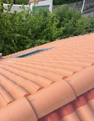 Toiture rénovée avec tuiles rouges en terre cuite.